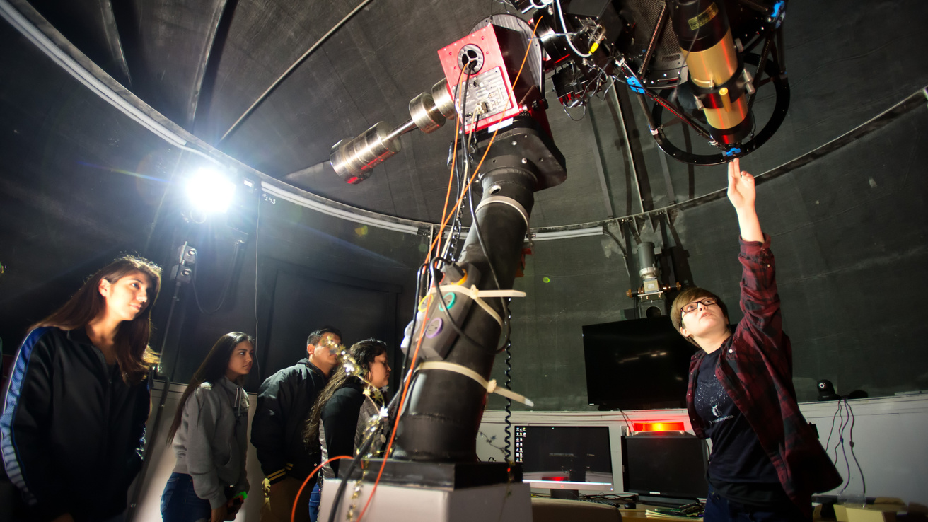 Students are shown equipment on the VAO telescope by an observatory staff member.